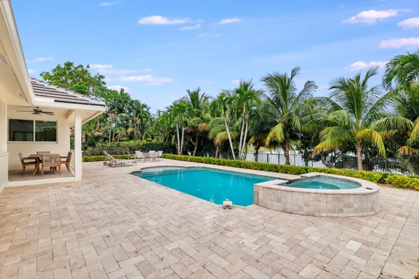 a view of a swimming pool with a yard and palm trees