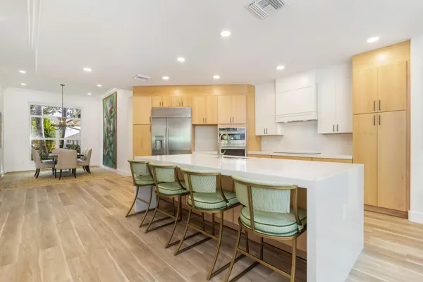 a kitchen with stainless steel appliances granite countertop a table chairs sink and cabinets