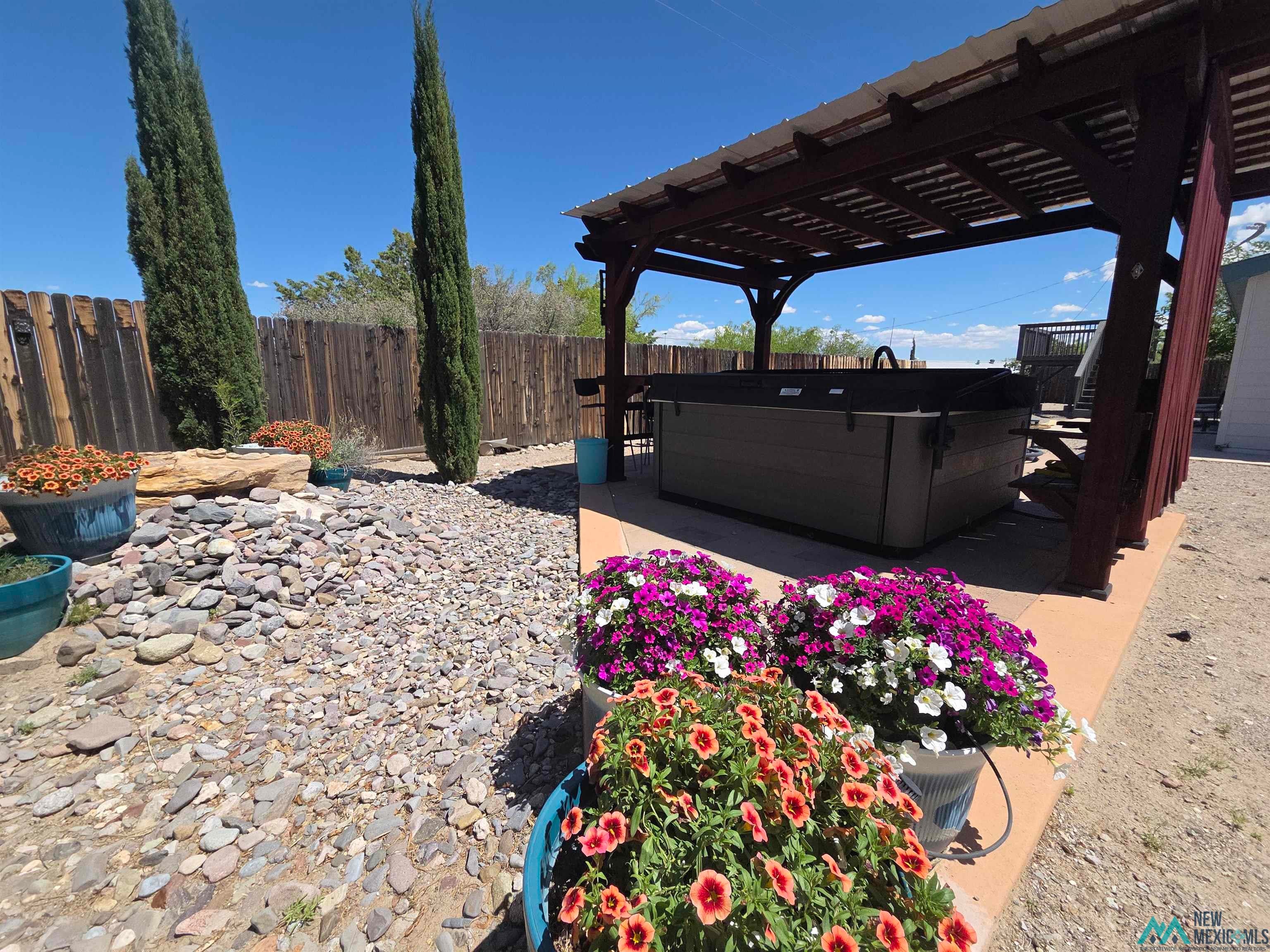 407 Bass Road Elephant Butte, NM 87935 - Photo 19 of 54 Fenced backyard featuring a wooden deck, a hot tub, and a pergola
