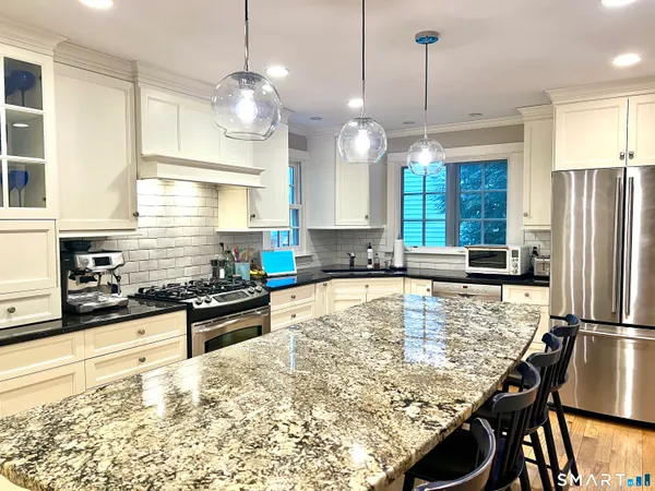 a kitchen with stainless steel appliances granite countertop a stove a refrigerator a kitchen island a sink and a refrigerator