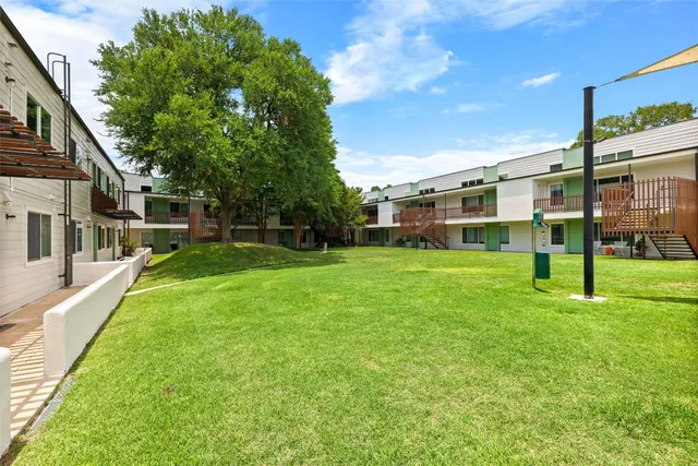 a view of a house with a big yard and large trees