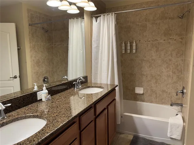 a bathroom with a granite countertop sink and a bathtub