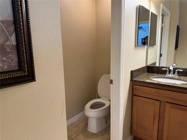 a bathroom with a granite countertop toilet sink and mirror
