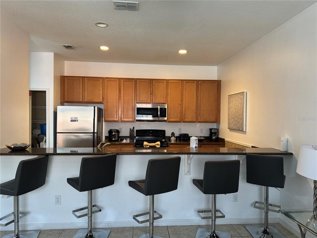 8975 Candy Palm Road Kissimmee, FL 34747 - Photo 6 of 27 a kitchen with stainless steel appliances granite countertop a stove a sink a refrigerator and chairs