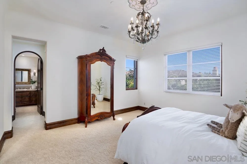 7748 Rd To Zanzibar San Diego, CA 92127 - Photo 30 of 32 a bedroom with a large bed and a chandelier