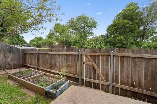 a view of a backyard with wooden fence and a large tree