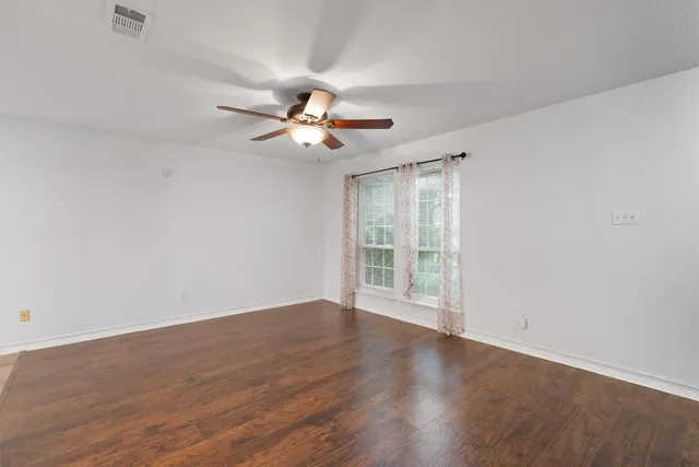 a view of an empty room with a window and wooden floor