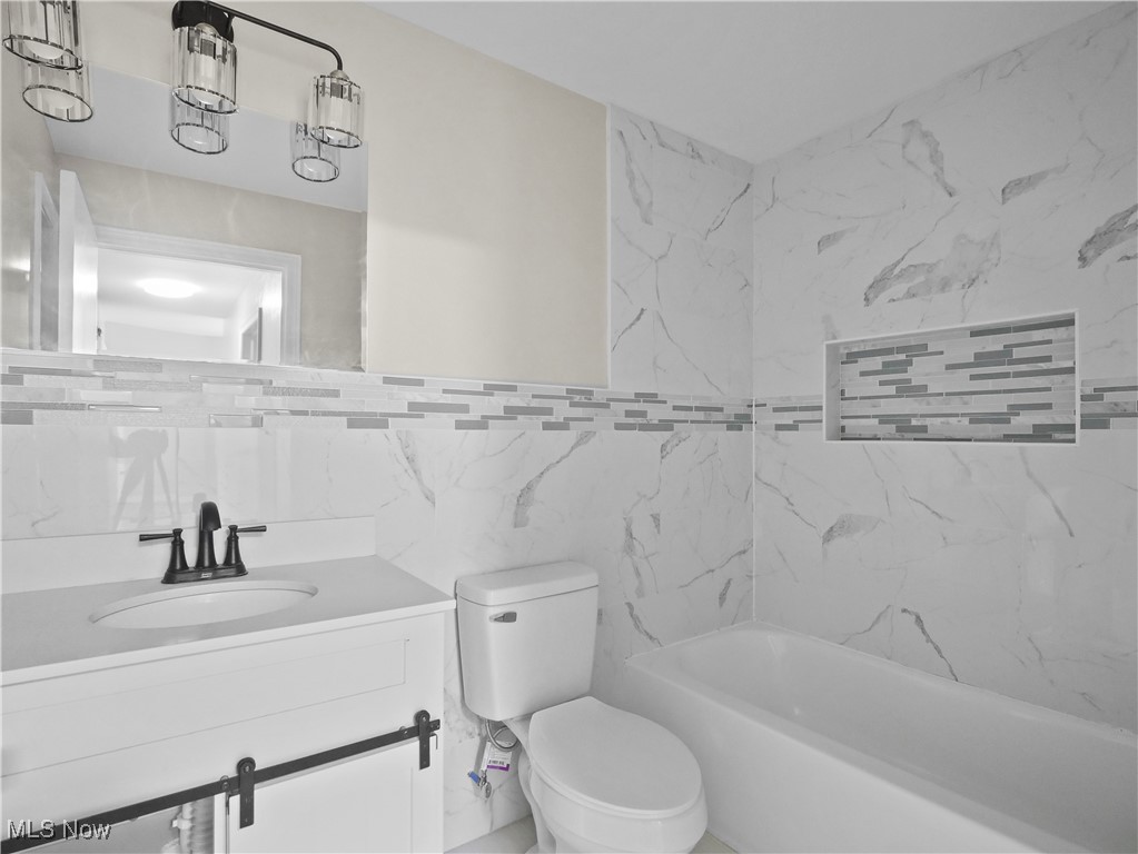 32 North Hillside Road Canfield, OH 44406 - Photo 12 of 38 Full bathroom with tile walls, vanity, tiled shower / bath combo, and toilet
