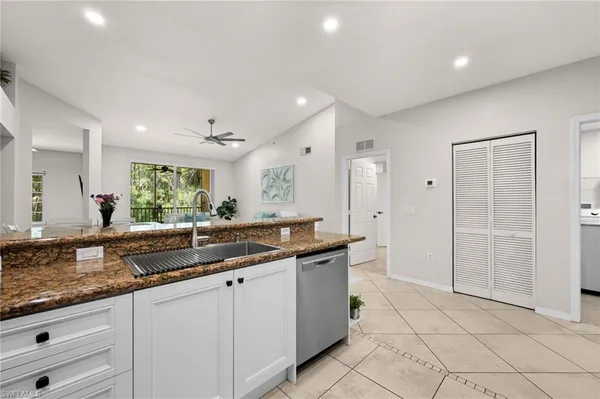a large kitchen with granite countertop a sink and white cabinets