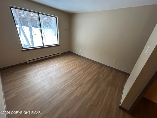 an empty room with wooden floor and windows