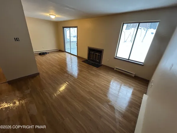 an empty room with wooden floor and windows
