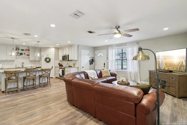 a living room with furniture kitchen view and a wooden floor