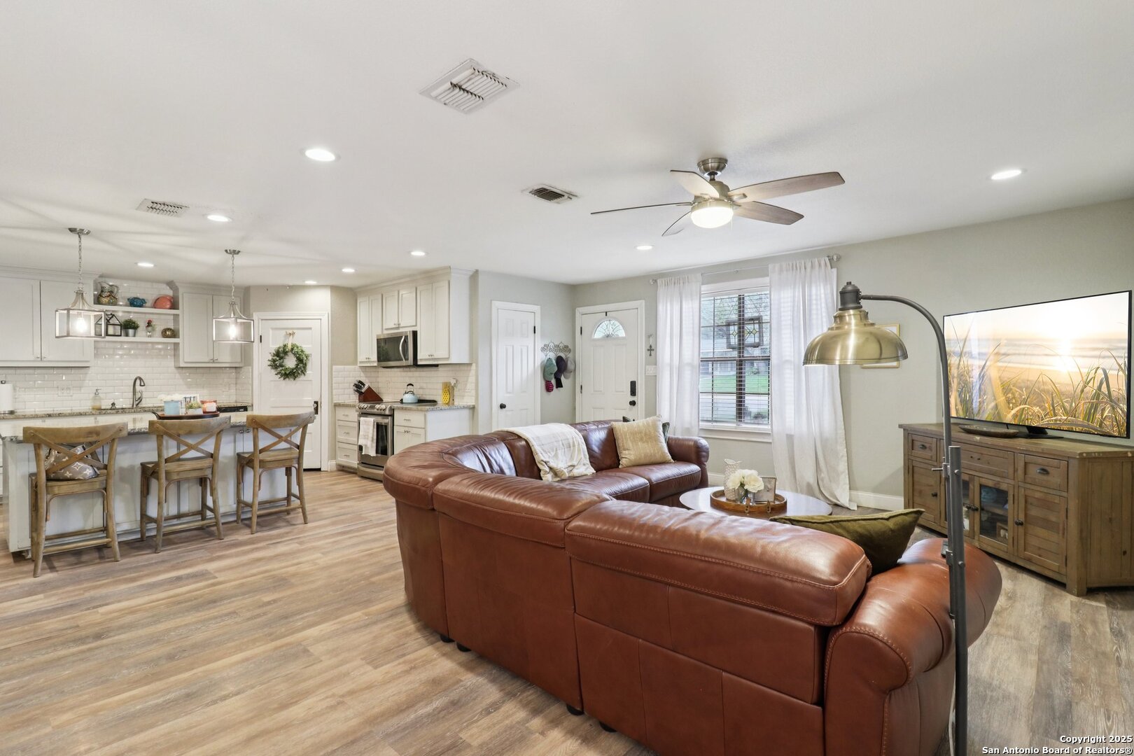 a living room with furniture kitchen view and a wooden floor