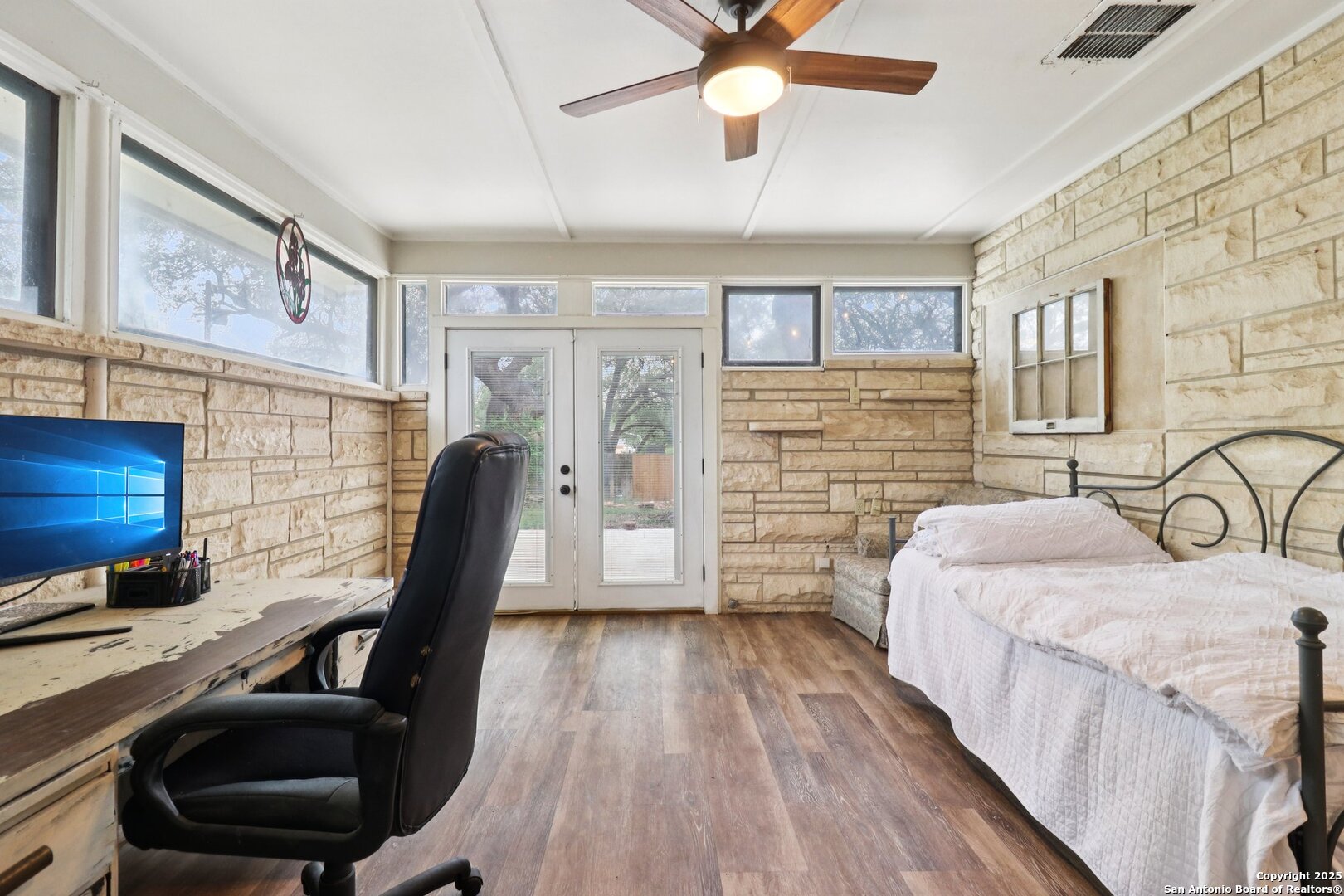 503 Mockingbird Lane Devine, TX 78016 - Photo 13 of 49 a bedroom with a bed a desk and chair with the wooden floor