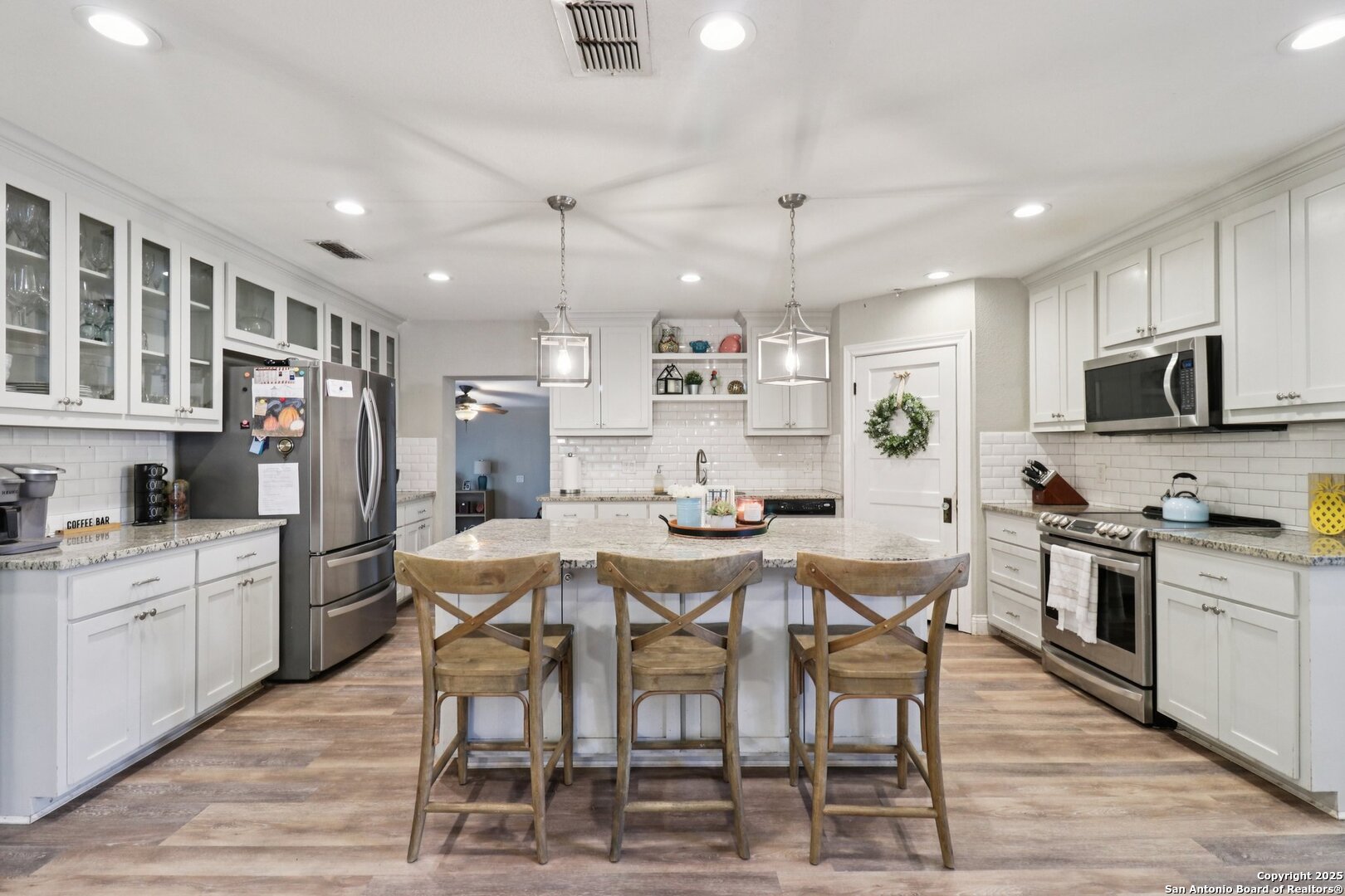 503 Mockingbird Lane Devine, TX 78016 - Photo 8 of 49 a kitchen with stainless steel appliances kitchen island granite countertop a dining table chairs refrigerator and sink