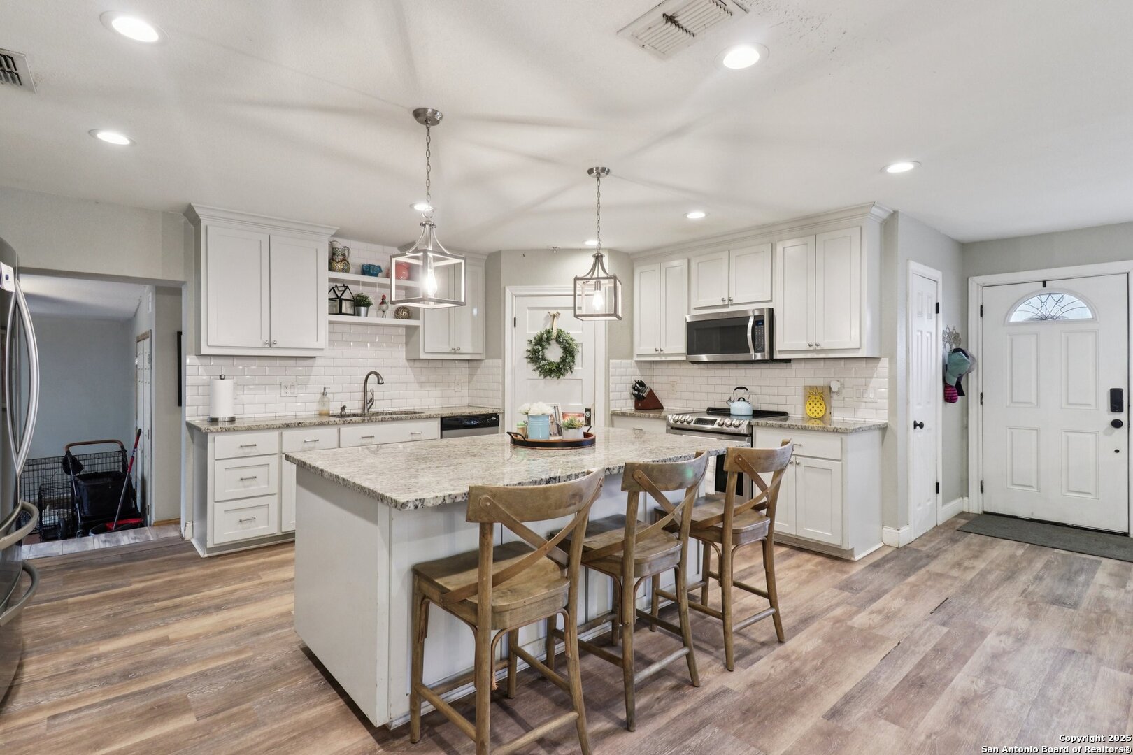 503 Mockingbird Lane Devine, TX 78016 - Photo 9 of 49 a kitchen with stainless steel appliances granite countertop a stove top oven a refrigerator a sink and white cabinets with wooden floor