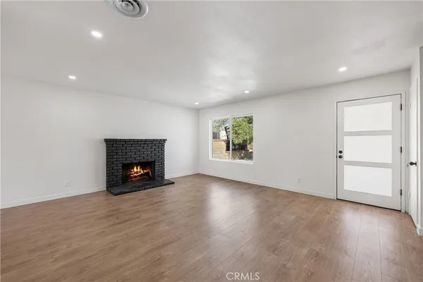 an empty room with wooden floor fireplace and windows