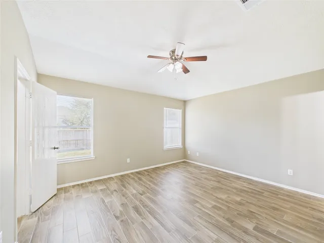 a view of empty room with wooden floor and fan