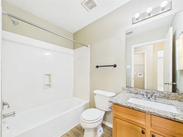a bathroom with a granite countertop sink a toilet and shower