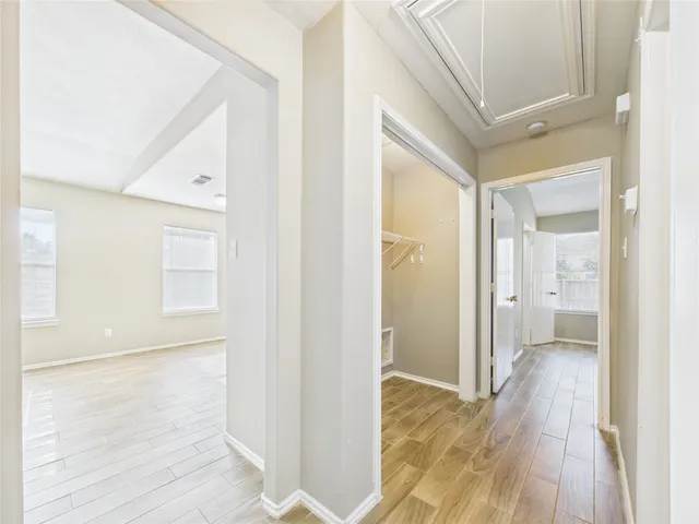 a view of a hallway with wooden floor and a bathroom