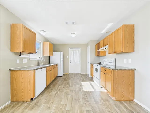 a large kitchen with stainless steel appliances granite countertop a sink a stove cabinets and wooden floor