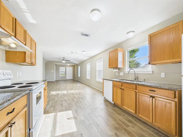 a view of a kitchen counter top space a sink wooden floor and a window
