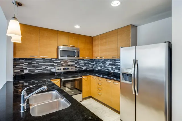 a kitchen with stainless steel appliances granite countertop a sink and a refrigerator