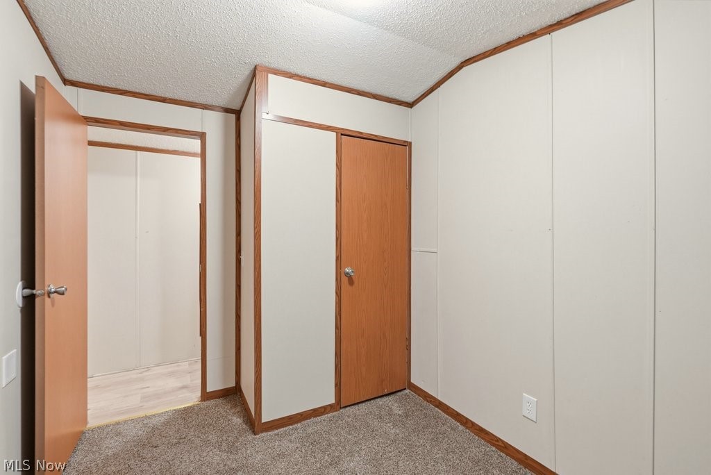 6507 Robby Lane Ravenna, OH 44266 - Photo 19 of 25 Unfurnished bedroom with a textured ceiling, light colored carpet, a closet, and crown molding