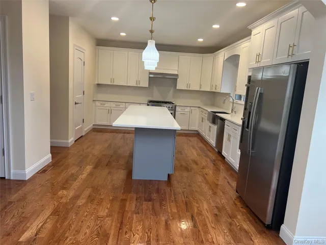 a large kitchen with kitchen island a large counter top stainless steel appliances and cabinets