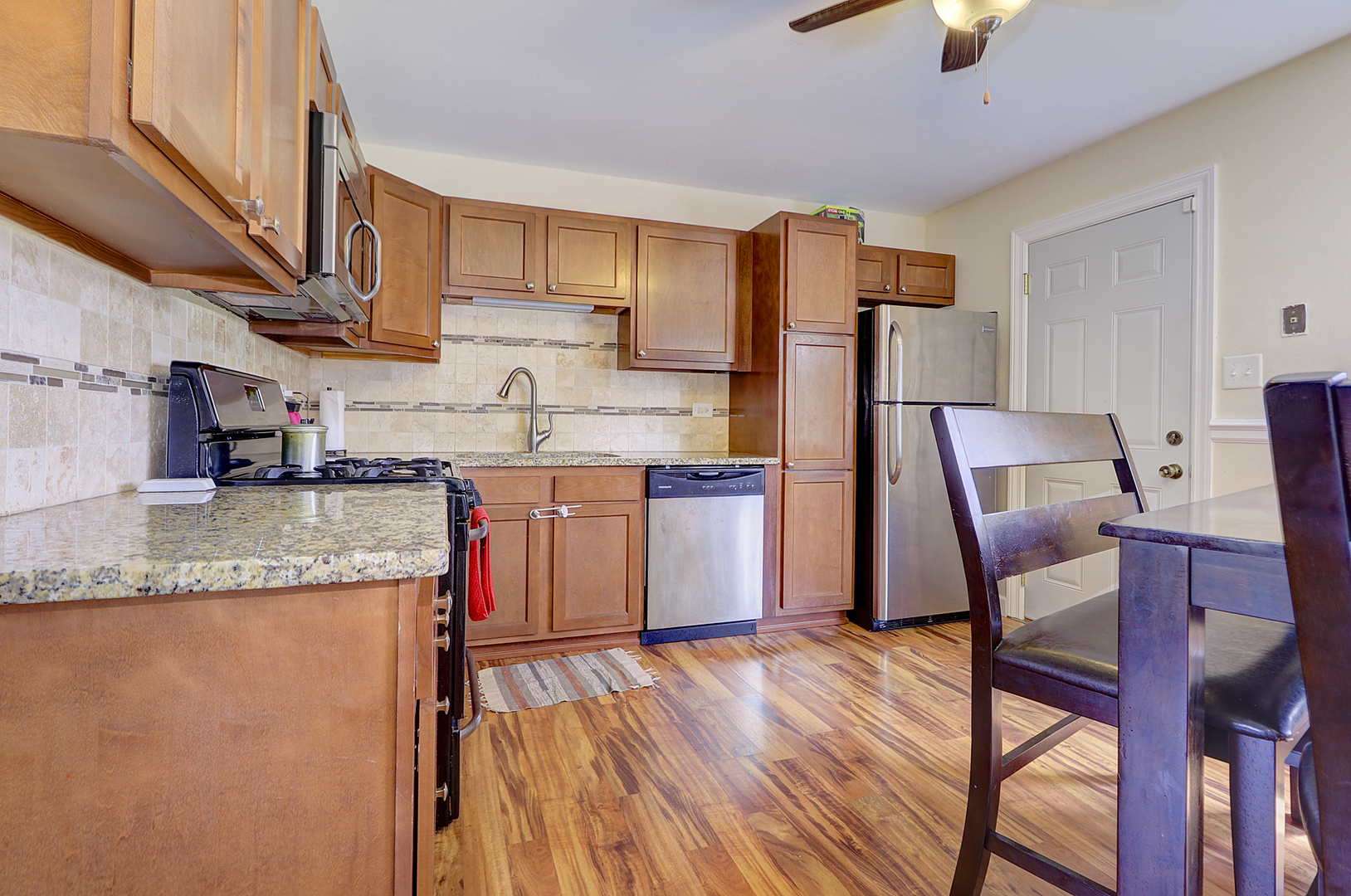 231 Murphy Drive Romeoville, IL 60446 - Photo 7 of 14 a kitchen with stainless steel appliances granite countertop a table chairs sink and cabinets