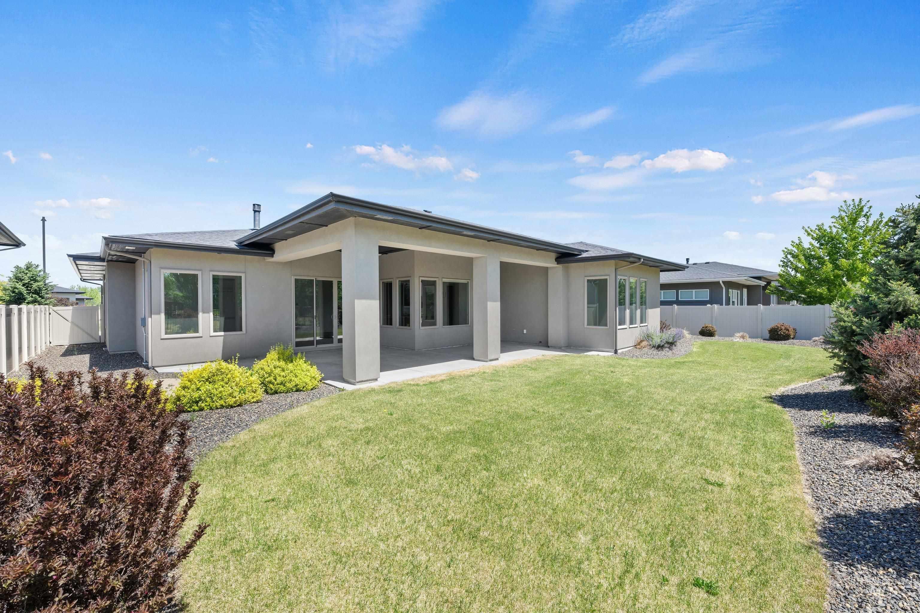 4447 East Copper Point Drive Meridian, ID 83642 - Photo 34 of 41 Spacious rear exterior featuring a covered patio, multiple windows, and a landscaped yard with decorative gravel and established shrubbery