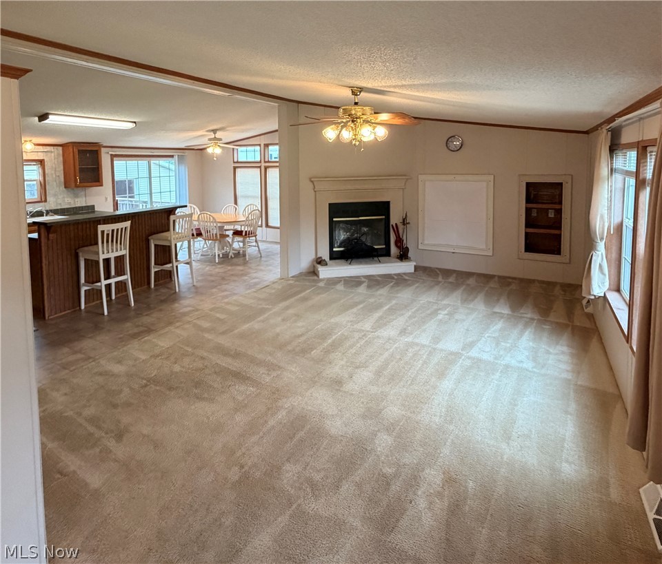 Spacious living area with a fireplace, ceiling fan, and built-in shelving