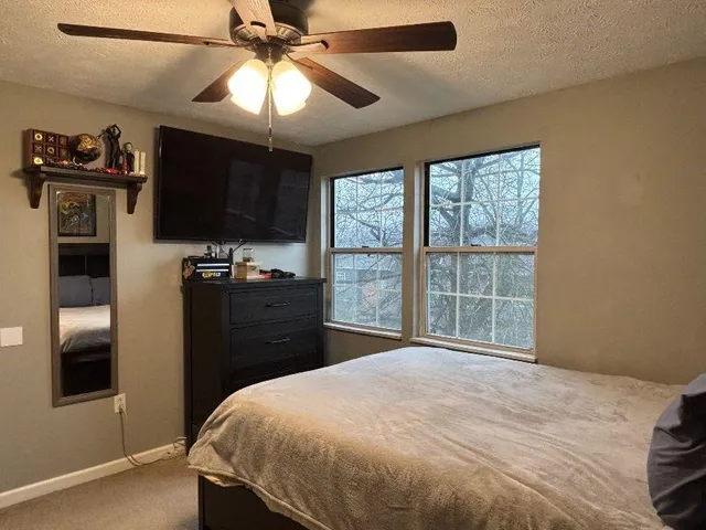 a bedroom with a bed and a flat tv screen on dresser