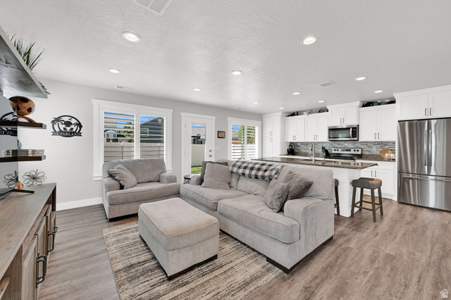2777 West 4175th Street South, Unit 232 Roy, UT 84067 - Photo 12 of 27 Open-concept living space/kitchen featuring LVP flooring, recessed lighting, and white plantation shutters