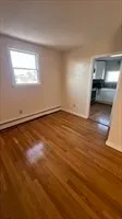 an empty room with wooden floor cabinet and windows