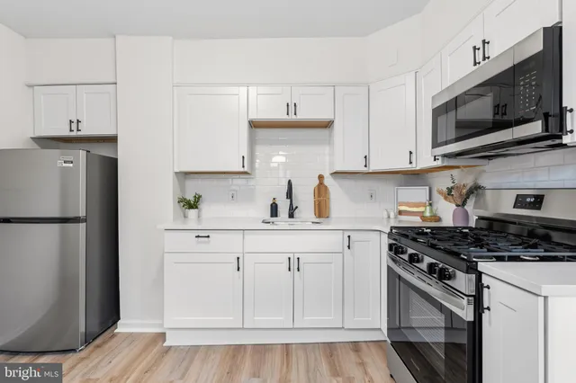 a kitchen with stainless steel appliances white cabinets and a stove top oven