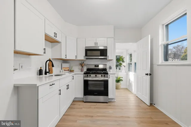 a kitchen with stainless steel appliances granite countertop a stove top oven a sink and a refrigerator