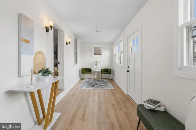 a view of a hallway to a livingroom with wooden floor and furniture