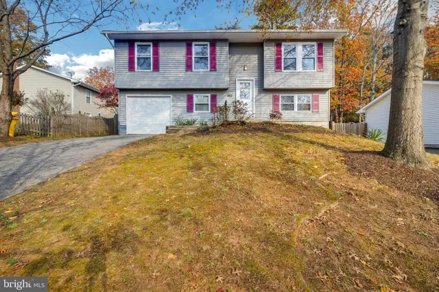 a front view of a house with large trees