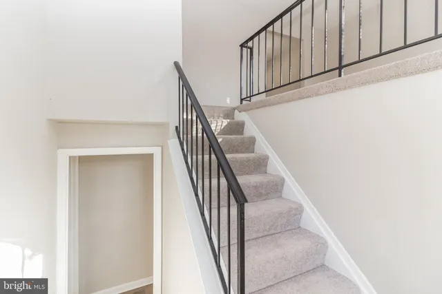 a view of staircase with railing and white walls