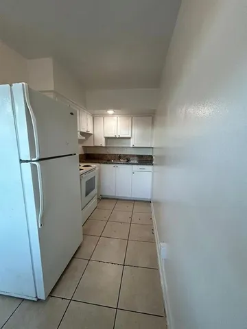 a kitchen with a refrigerator a stove top oven and cabinets