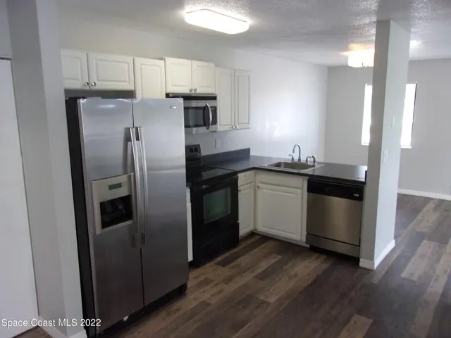 a kitchen with stainless steel appliances a refrigerator a sink and wooden floors