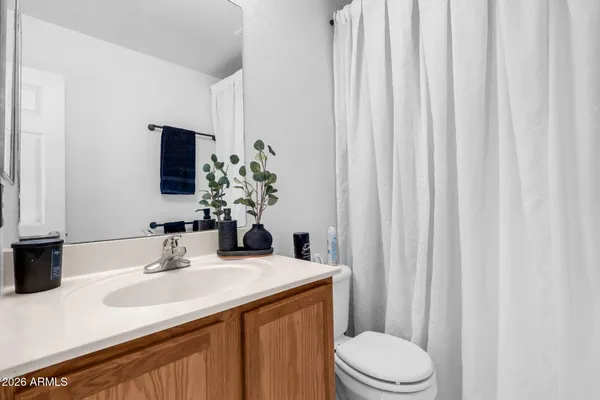 a bathroom with a sink a toilet a mirror and shower curtain