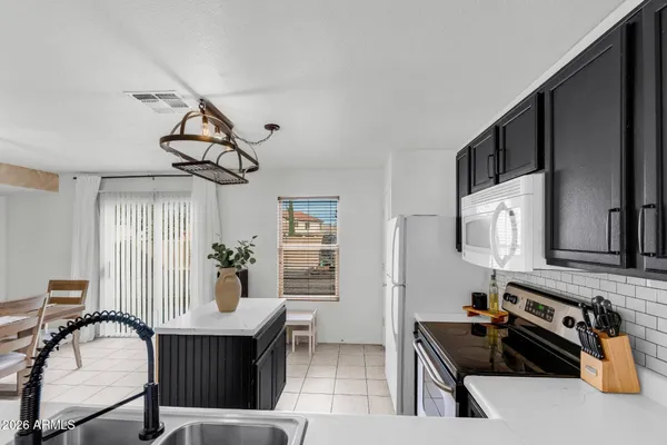 a kitchen with stainless steel appliances a sink a stove a refrigerator cabinets and furniture