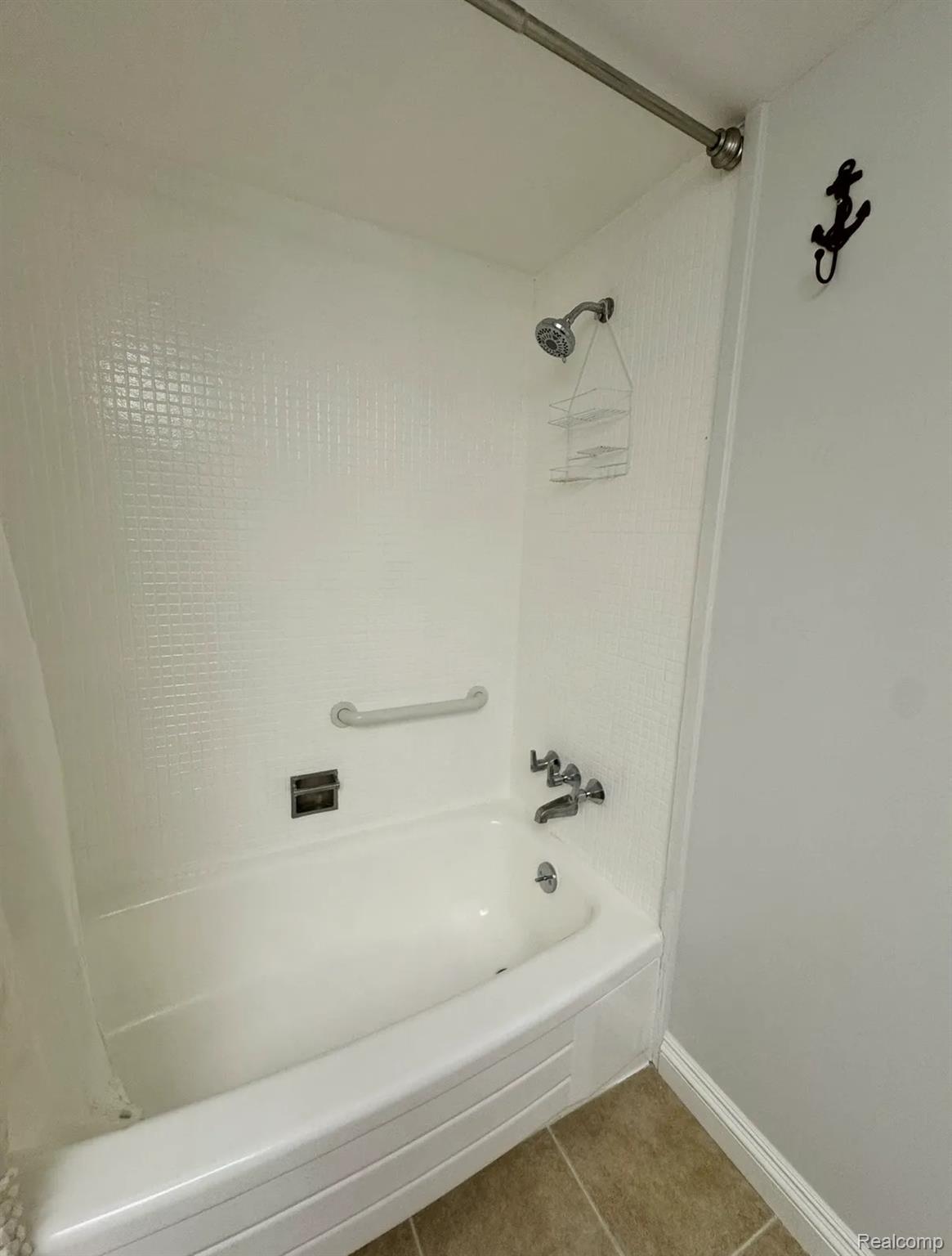2247 Walton Blvd. Rochester, MI 48309 - Photo 11 of 12 White tub and shower combination featuring a grab bar, chrome fixtures, and textured wall paneling