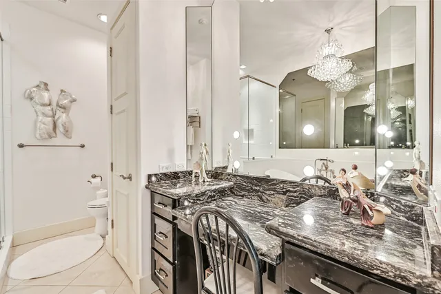 a bathroom with a granite countertop sink a toilet a mirror and shower