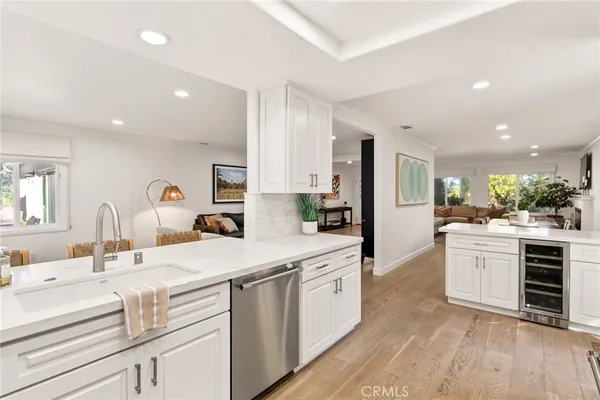 a living room with stainless steel appliances kitchen island granite countertop a refrigerator a stove top oven and a dining table with wooden floor