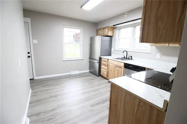 a kitchen with stainless steel appliances a sink a stove a refrigerator cabinets and a window