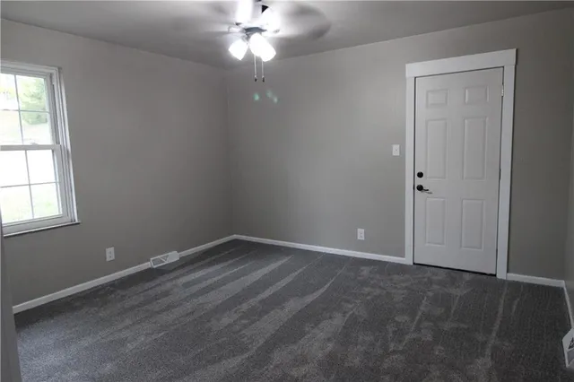 an empty room with a chandelier fan and windows