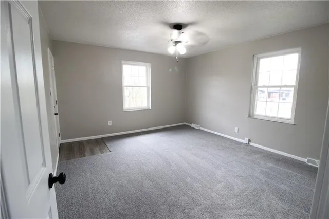 an empty room with windows and chandelier fan